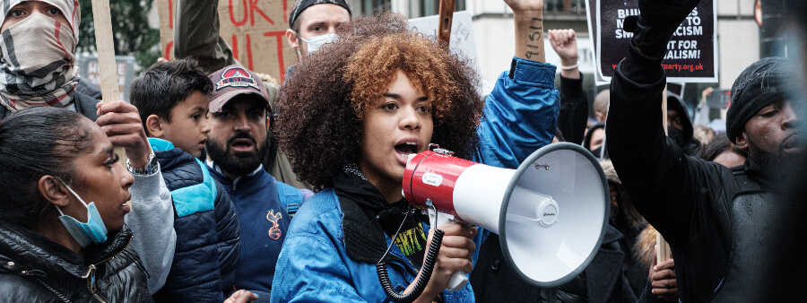 Dia da democracia: fotografia de um protesto com foco em uma mina que grita em um megafone.